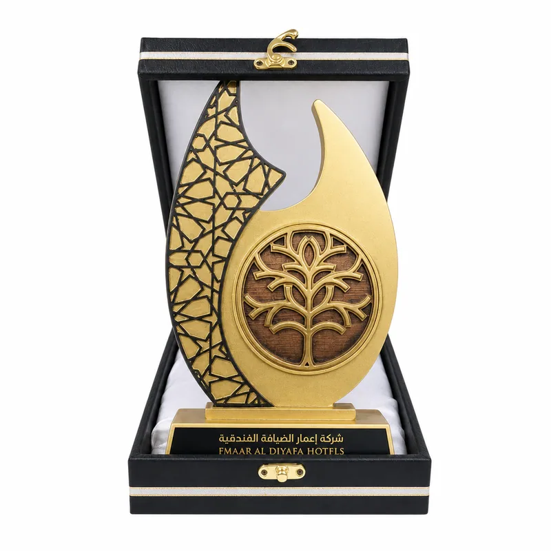 Gold trophy with an Islamic geometric panel and an engraved tree motif, presented in a black presentation case by Emaar Al Diyafa Hotels.